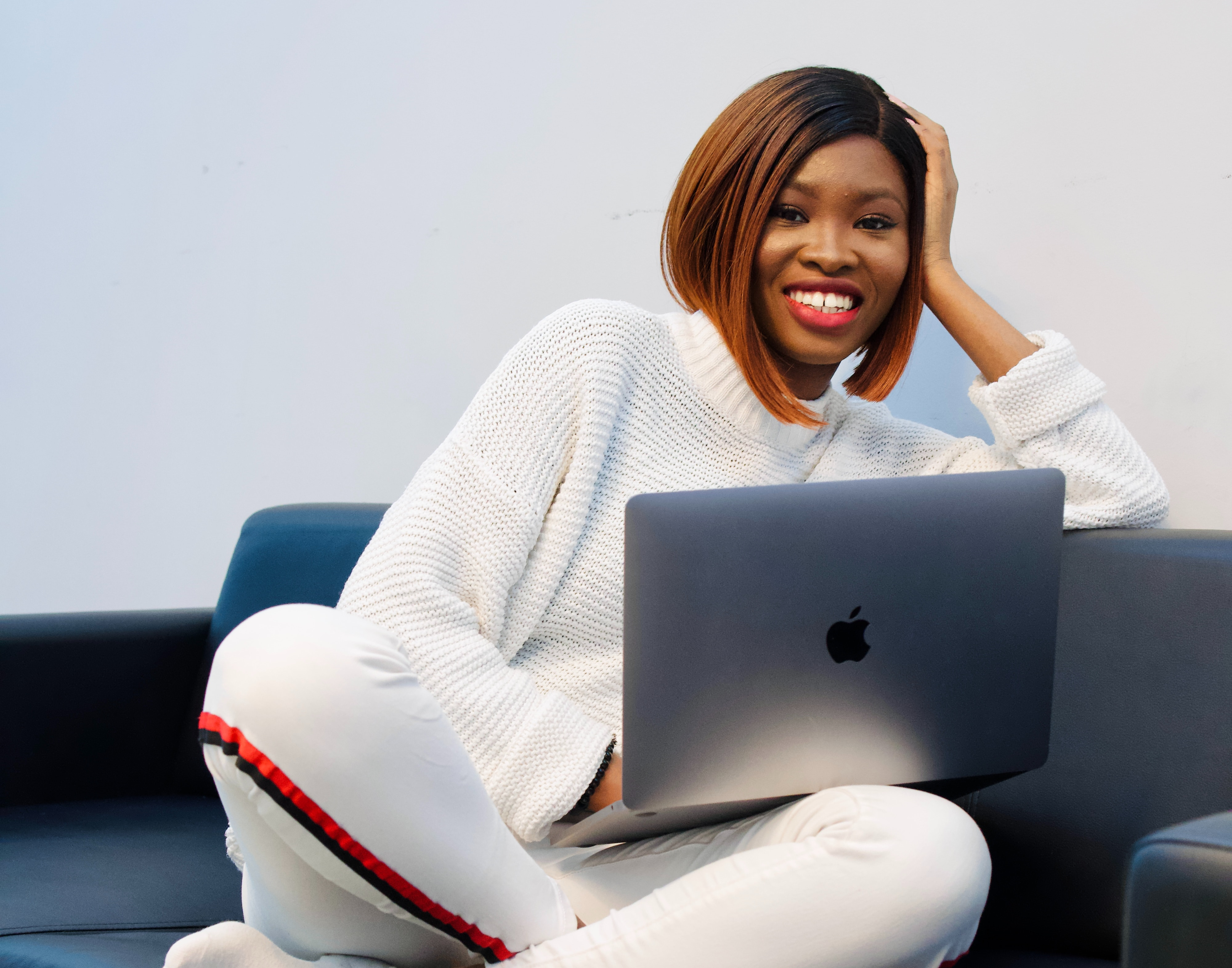 Lady smiling and relaxing on a sofa with a laptop while using a user-friendly software application.